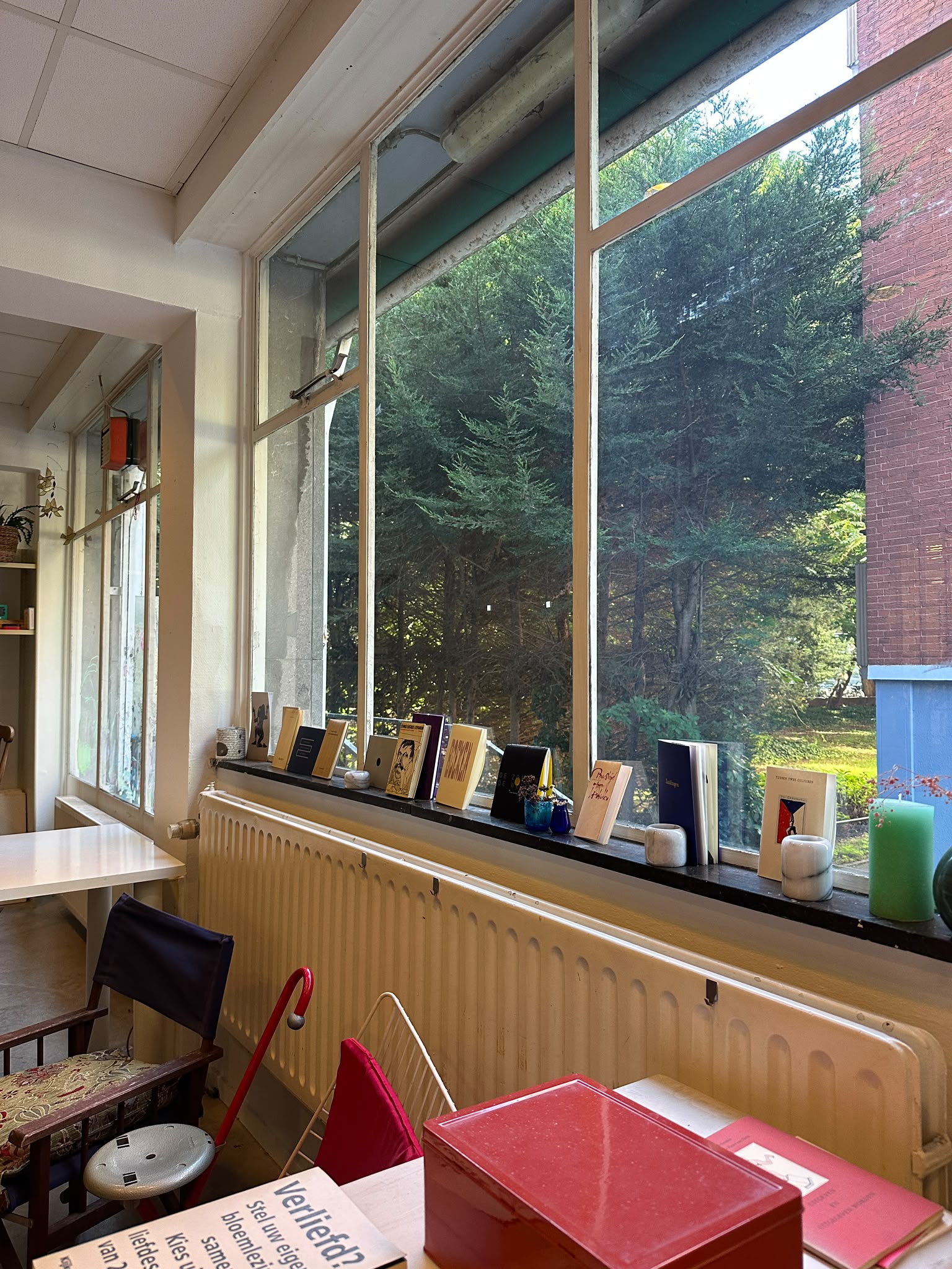 De vensterbank met boekjes in Atelier 0.001, met uitzicht op het groen